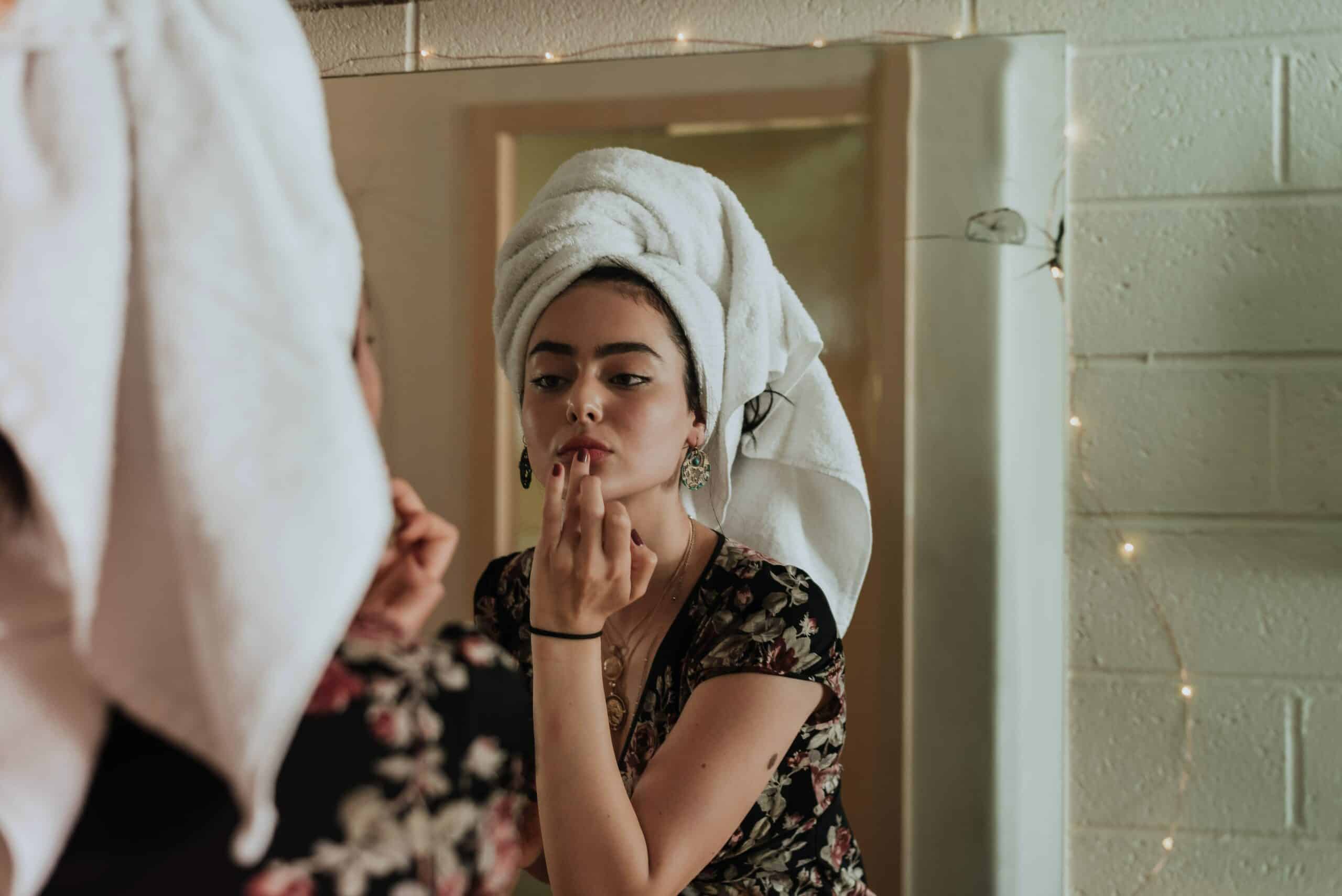 Jeune femme qui se démaquille face au miroir