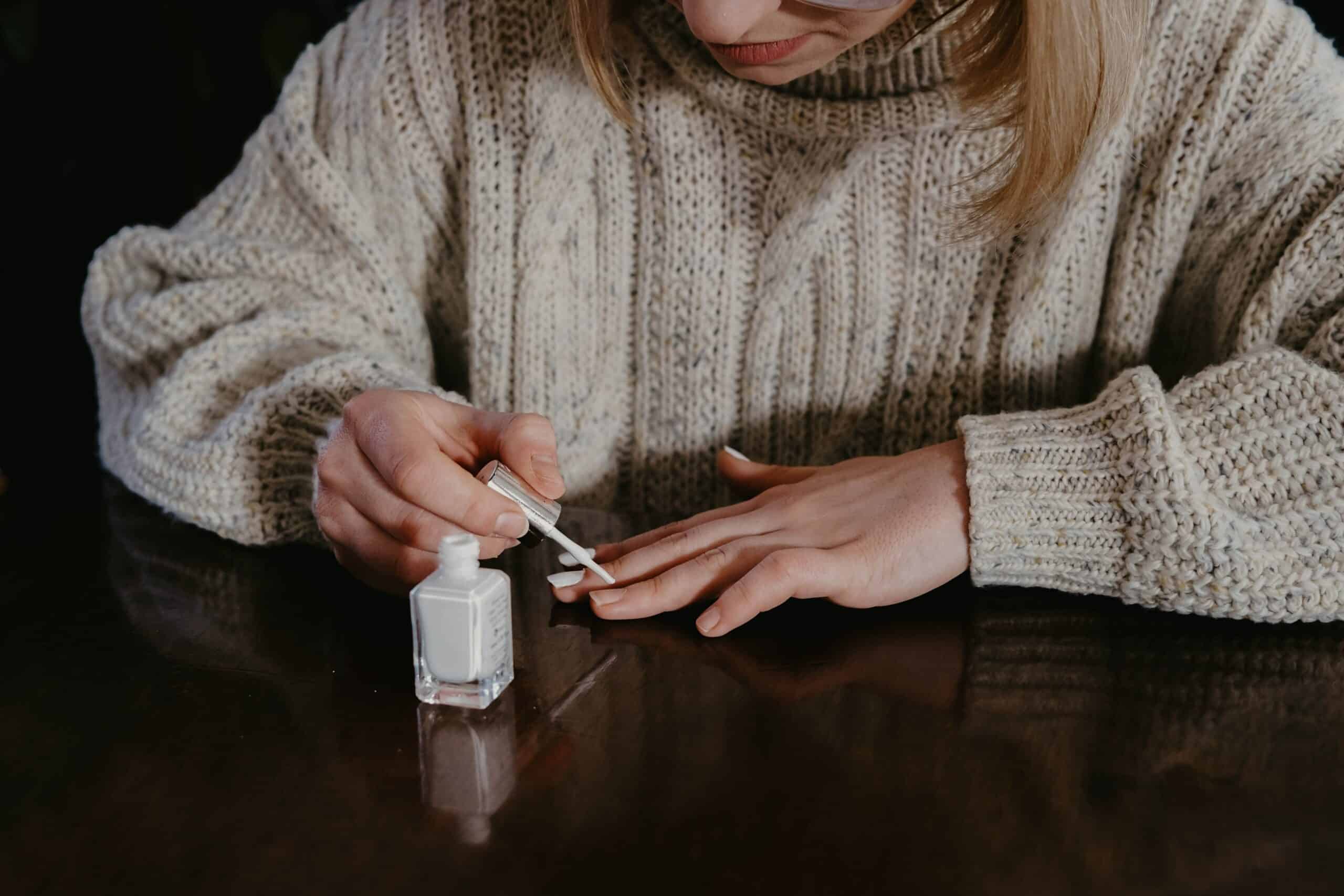 Jeune femme qui se met du vernis blanc sur les ongles